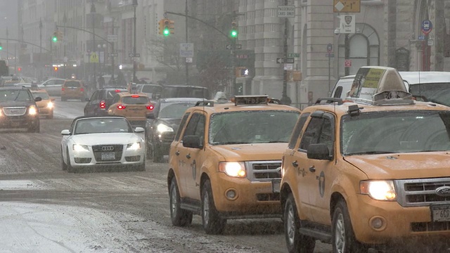 在一个大雪纷飞的冬日，纽约市中央公园外的中央公园西大街上，车辆在行驶。视频素材