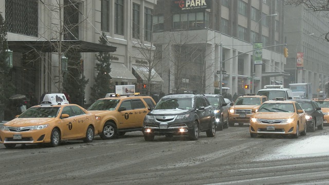 在一个大雪纷飞的冬日里，纽约街道上的车辆在移动。在画面中，交叉车辆转向街道。视频素材