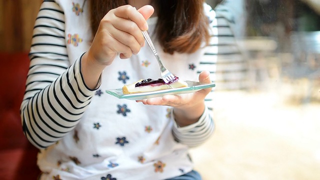 年轻女子在吃蓝莓芝士派蛋糕视频素材