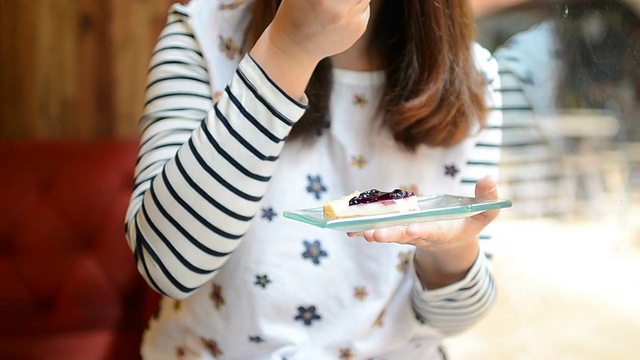 年轻女子在吃蓝莓芝士派蛋糕视频素材