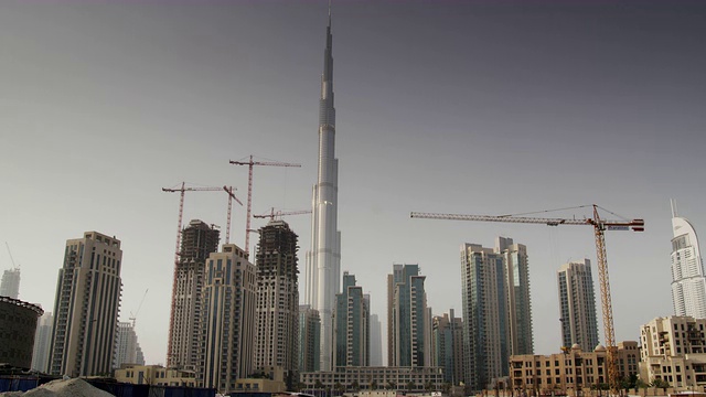 在阿拉伯联合酋长国迪拜，世界上最高的建筑哈利法塔(Burj Khalifa)被更小的摩天大楼和起重机包围着。视频素材