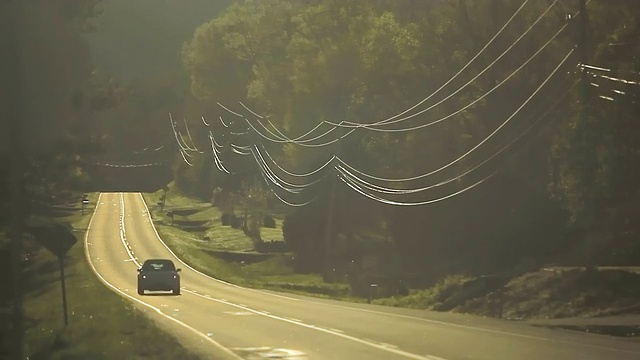 在阳光的照耀下，狭窄闪亮的乡村道路和汽车闪闪发光视频下载