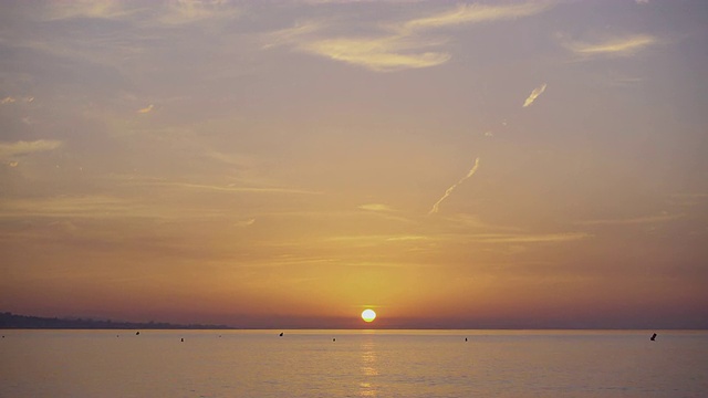 4K |夏日末巴塞罗那海滩的日出。我们可以看到平静的地中海在对称的广角拍摄，太阳在中间，地平线在较低的三分之一。视频素材