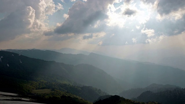 山脉和戏剧性的云和阳光穿过山地景观。视频素材