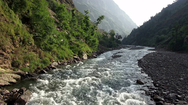 近距离拍摄奔流的河流沿着山谷底部在山区。视频素材