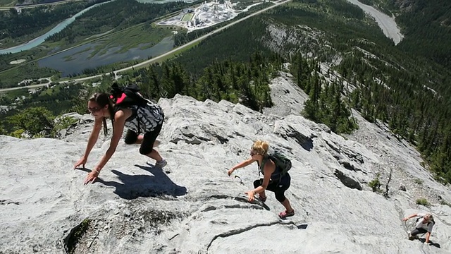 十几岁的徒步旅行者攀登山谷之上的山脊视频素材