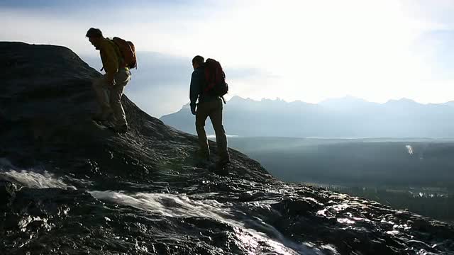 徒步旅行者穿过小溪，攀登山脊视频素材