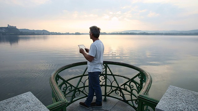 男子进入湖上的观景区，使用数字平板电脑视频素材