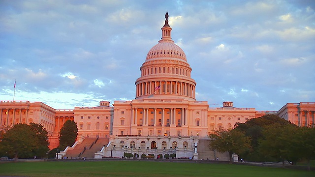 这是美国华盛顿特区国会大厦顶上的国旗，在夕阳的照耀下，建筑物被染成了红色视频素材