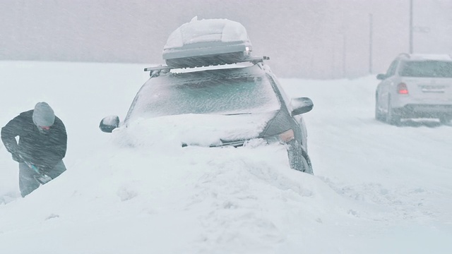 一名男子正在把他的车从雪中挖出来视频素材