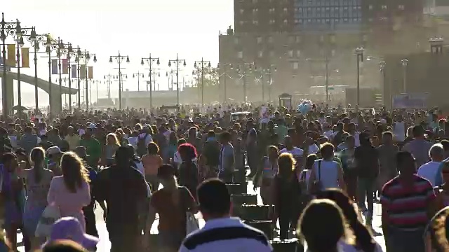 TL PAN摄像机捕捉到了海滩上的人们和走在科尼岛木板路上的人群。视频素材