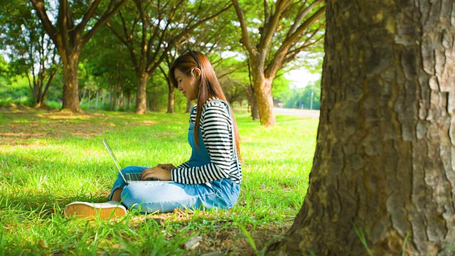 亚洲女人在公园里用笔记本电脑视频素材