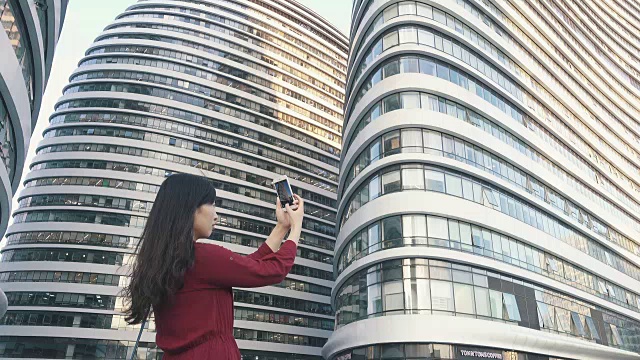 年轻女子用智能手机在城市拍照视频素材