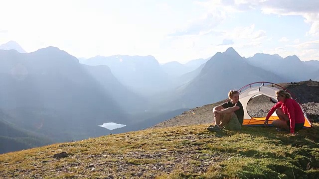 徒步旅行者穿过高高的山脊走向帐篷营地视频素材