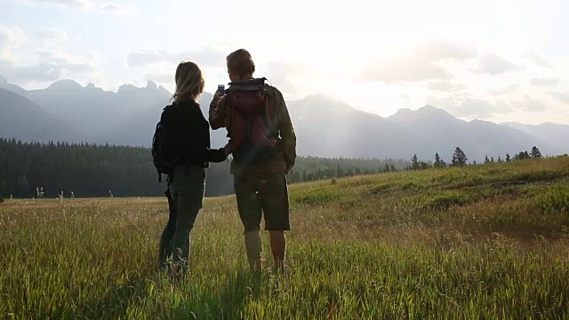 情侣徒步穿越高山草地，用智能手机拍照视频素材