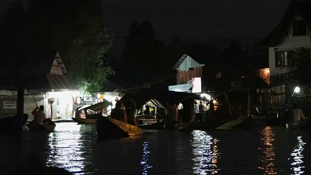 这是克什米尔斯利那加达尔湖的米纳集市上繁忙的夜市，有纪念品商店和其他船只视频素材