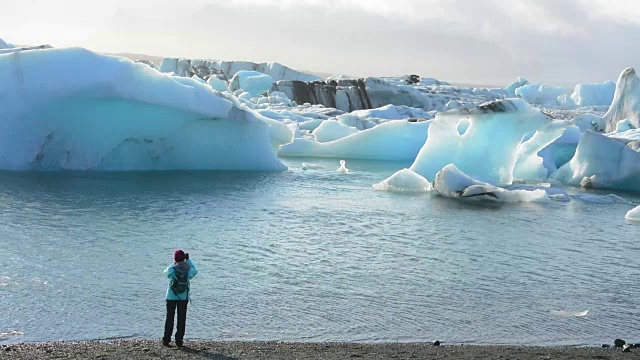 在冰岛东南部的Vatnajokull国家公园边缘，摄影师与Jokulsarlon冰川和泻湖上的冰山合影视频素材