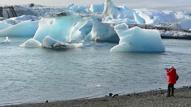 在冰岛东南部的Vatnajokull国家公园边缘，摄影师与Jokulsarlon冰川和泻湖上的冰山合影视频素材