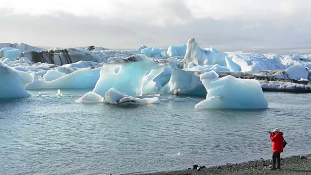 在冰岛东南部的Vatnajokull国家公园边缘，摄影师与Jokulsarlon冰川和泻湖上的冰山合影视频素材