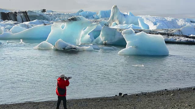 在冰岛东南部的Vatnajokull国家公园边缘，摄影师与Jokulsarlon冰川和泻湖上的冰山合影视频素材