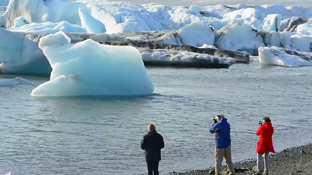 在冰岛东南部的Vatnajokull国家公园边缘，摄影师与Jokulsarlon冰川和泻湖上的冰山合影视频素材