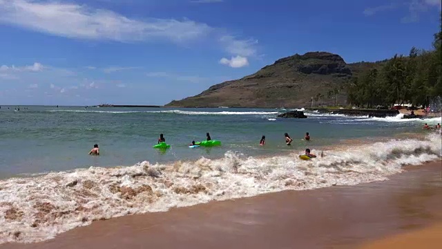 游客和当地人在考艾岛纳威利威利镇卡拉帕基海滩游泳视频素材