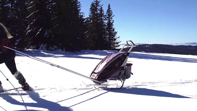 高清广角拍摄的年轻女性拉滑雪拖车在雪景视频下载