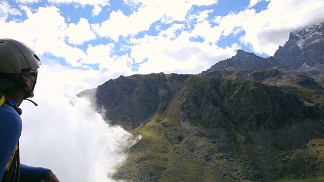 一个登山家从高山上看着云滚滚而来视频素材