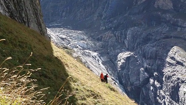 徒步旅行者沿着山间草地的小路攀登视频素材