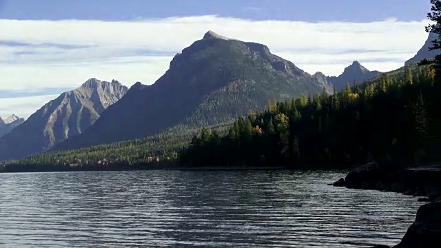 右宽镜头的山湖与岩石的海岸线和锯齿状的山峰在背景。视频素材