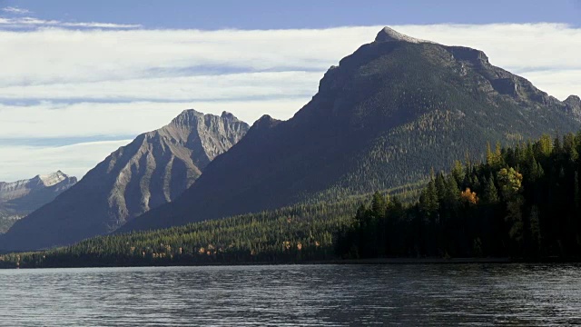 右宽镜头的山湖与岩石的海岸线和锯齿状的山峰在背景。视频素材