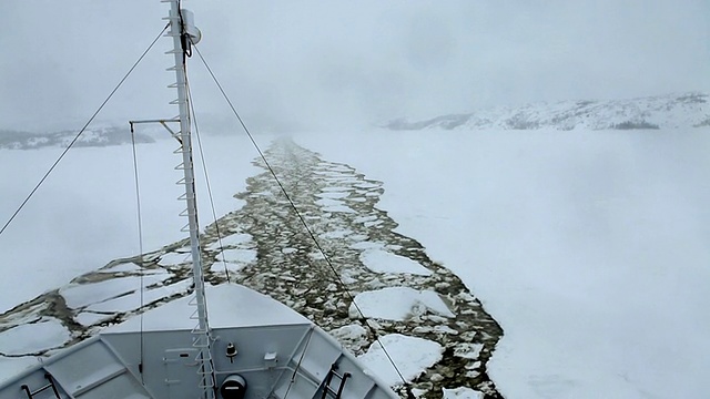 冰船在暴风雪中，在结冰的水面上沿着碎冰的痕迹航行的船视频素材