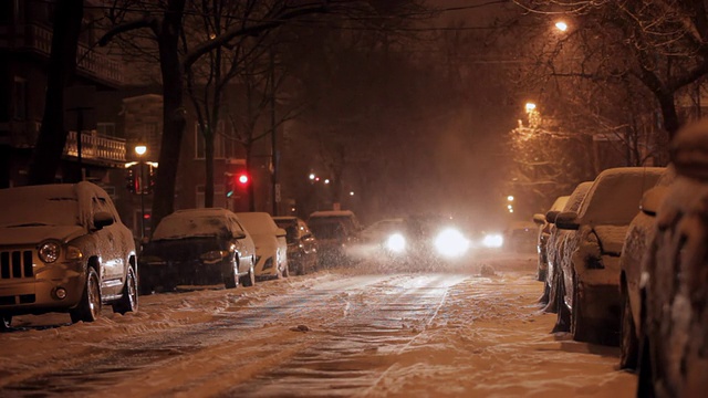 街上的汽车在黑暗的雪地里滚动视频素材