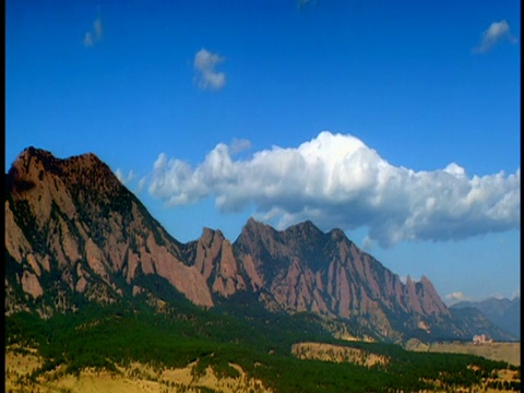 宽镜头长镜头时间流逝云在蓝色的天空在岩石山与树在基地/博尔德，科罗拉多州视频下载