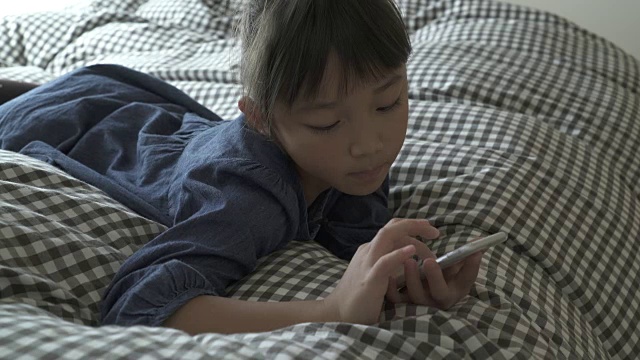 这个女孩正在床上用智能手机视频素材