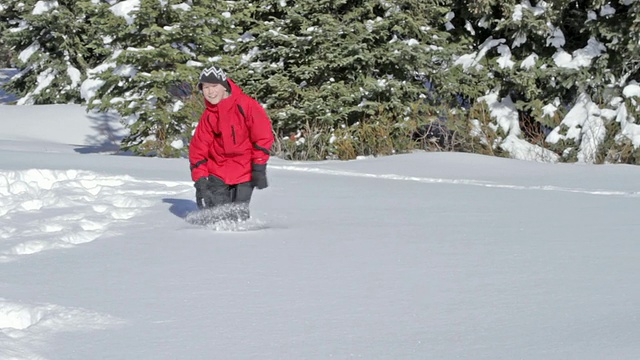 一个小男孩在一个阳光明媚的冬日里跑过雪地视频素材