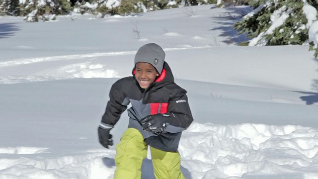 一个小男孩在一个阳光明媚的冬日里跑过雪地视频素材