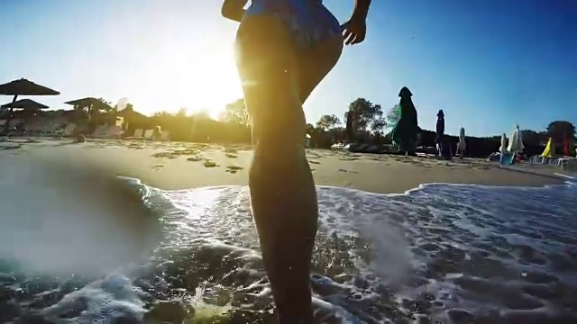 年轻女子跑向海滩，在日落溅起海水视频下载