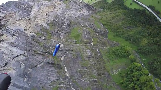 翼服飞行员从悬崖上跳下，在山谷上空翱翔视频素材