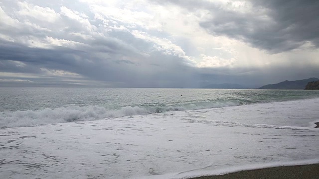 一名男子沿着海滩走向汹涌的海浪视频素材