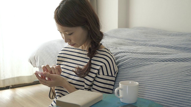 在房间里玩智能手机的女人视频素材