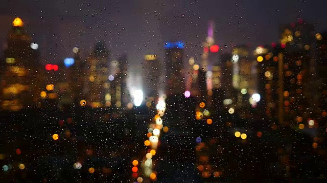 城市景观背景在一个雨夜。雨滴落在玻璃窗上视频素材