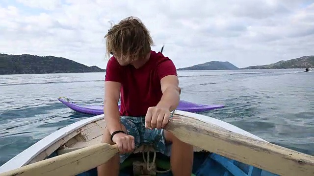 年轻男子划着小船驶入平静的海湾，年轻女子在一旁划着皮划艇视频素材