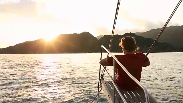 在风平浪静的海湾里，年轻人在帆船的吊杆上休息视频素材