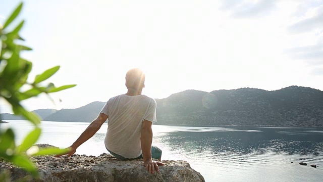 一个成熟的男人从岩石向宁静的海湾眺望视频素材