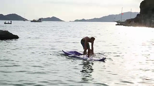 年轻的夫妇划着皮艇进入宁静的海湾，嬉戏着视频素材