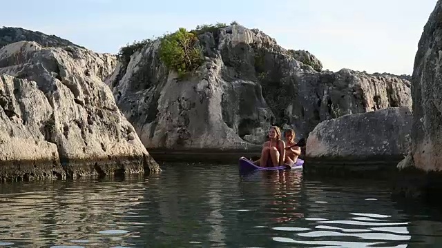 年轻夫妇划着皮艇穿过运河进入宁静的海湾视频素材