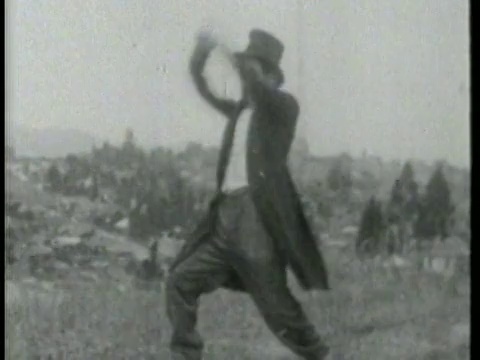 1915年，一名男子站在草地上，向画面外的某个人投掷炮弹视频素材