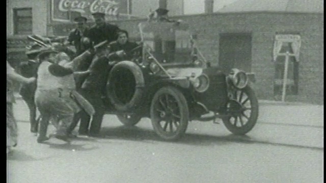 1915年，一群人开着车冲向Keystone Kops，指着城市街道视频素材