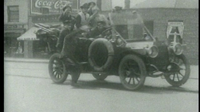 1915年的一辆车里装满了Keystone Kops和其他车辆，导致警察跌倒在城市街道上视频素材